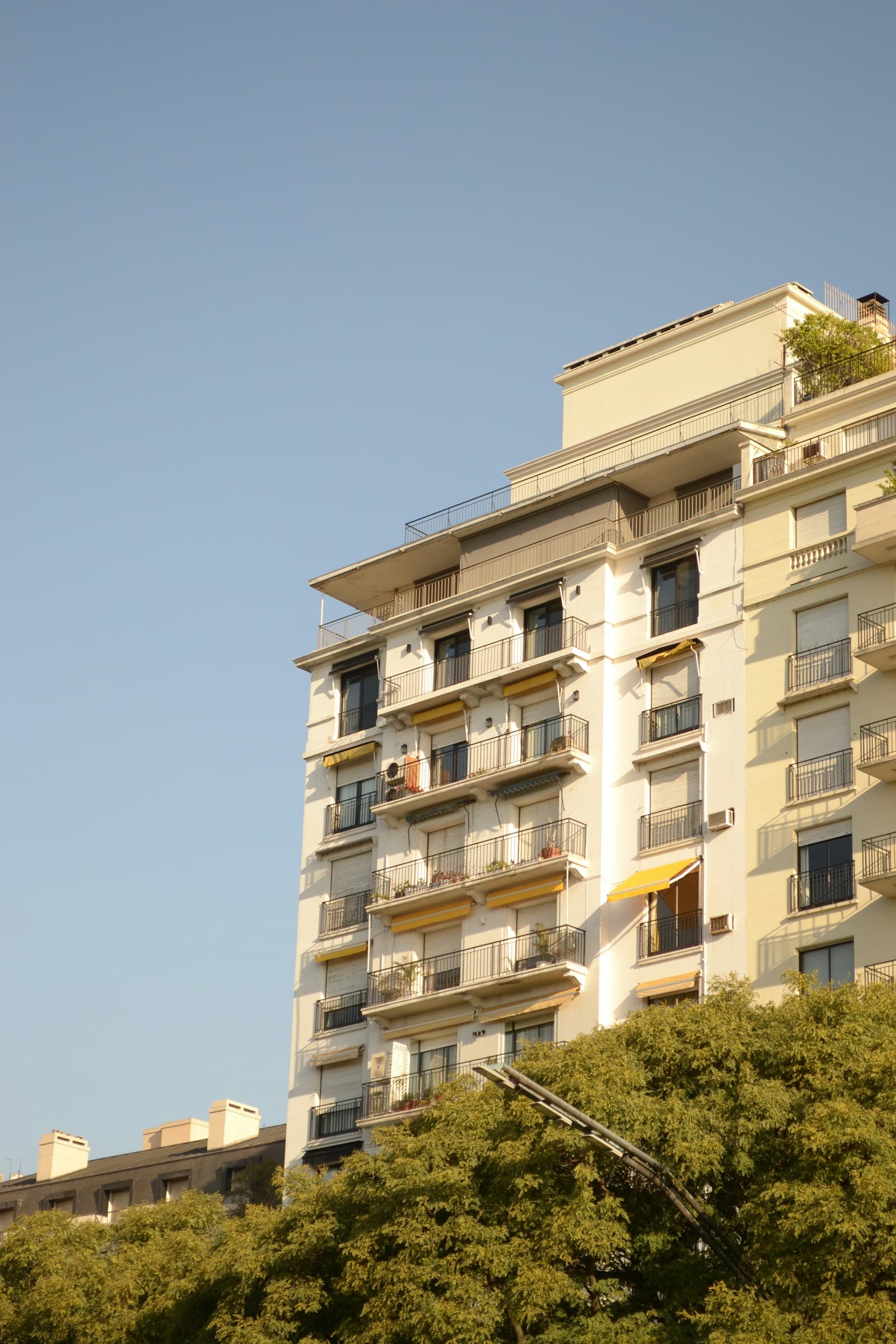 Edificio residencial de Buenos Aires con balcones y árboles en la vereda